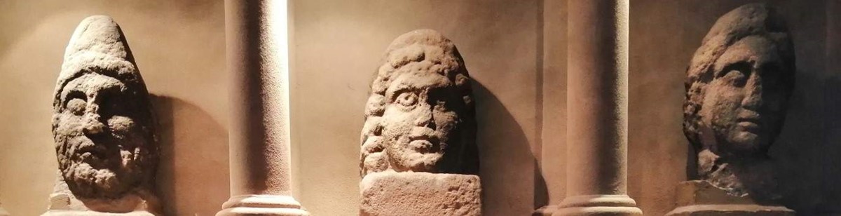 The image shows the strange Roman stone sculpture that can be seen in the City Museum and which were found near Burrow Heights. There are three very large heads, not finely carved, but almost cartoon-like.
