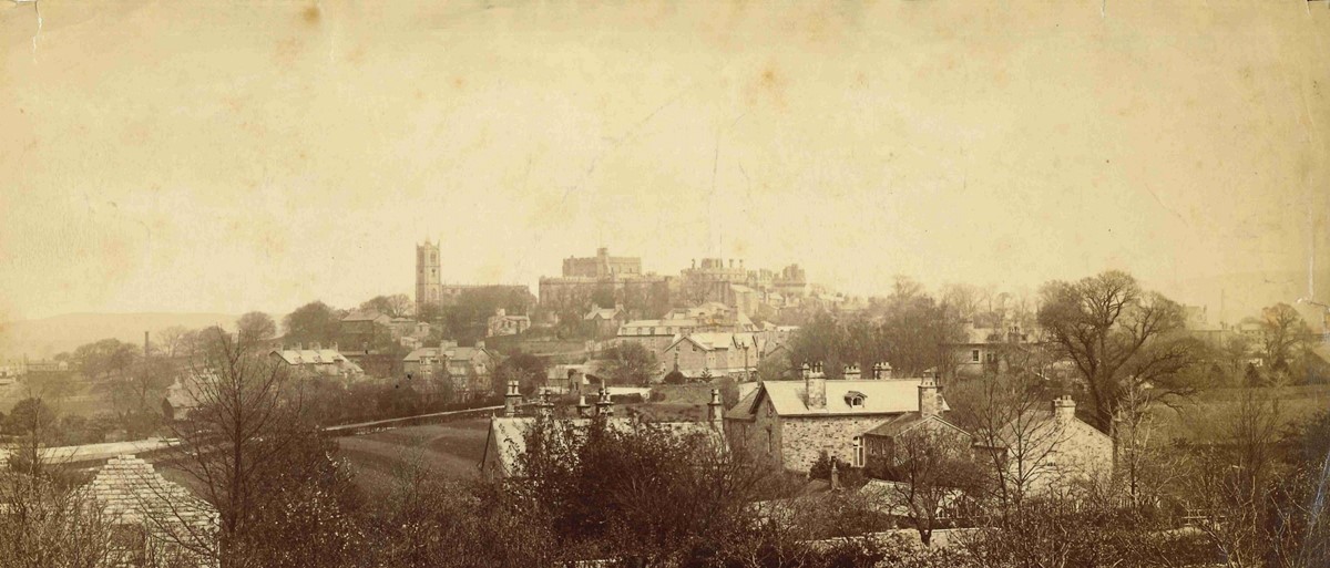 Sepia photo showing a view over the centre of Lancaster. The castle and priory church are prominent at the top of castle hill.