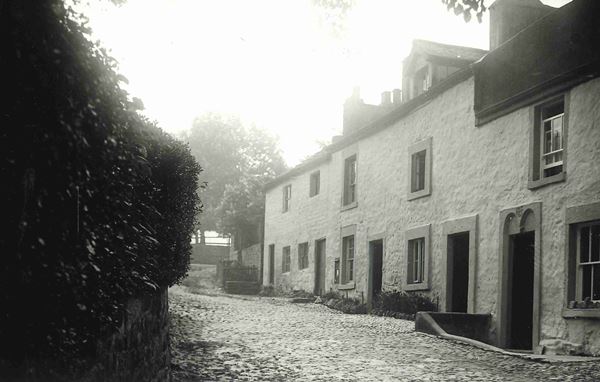 Photo of a row of old cottages in Aldcliffe beside a road running uphill.