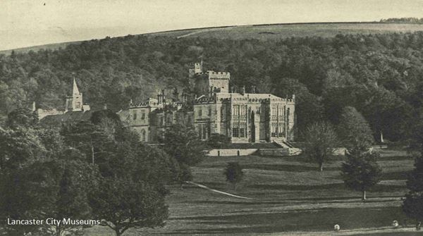 Black and white photo of Capernwray hall, a grand house with crenelations, surrounded by woods and parkland.