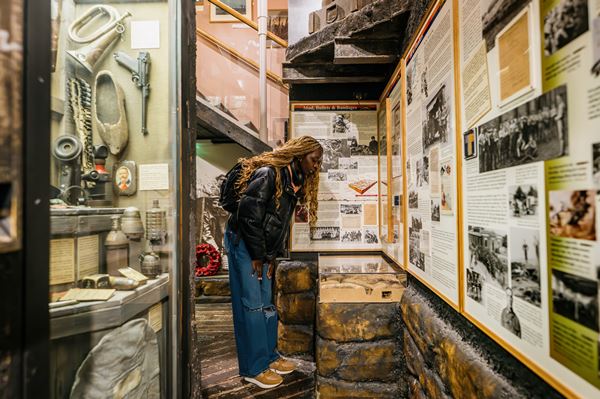 photo of a woman in a replica trench scene looking at displays of WW1 objects