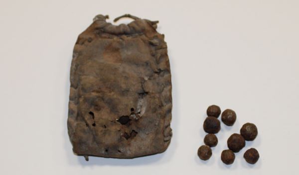 photo of a simple leather pouch and a handful of roughly shaped iron balls of various sizes.