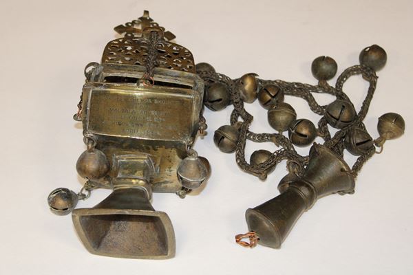 photo of an ornate metal censer, shaped like a square lidded goblet and suspended from chains hung with small bells.