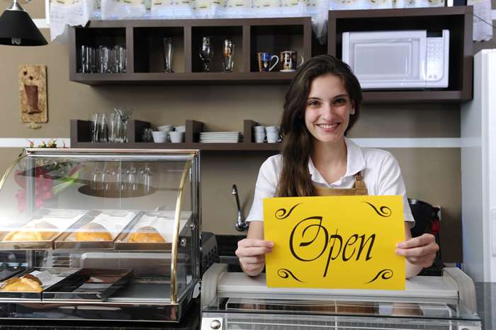 Cafe owner holding up an open sign