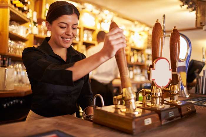 Woman pulling a pint of beer at a bar